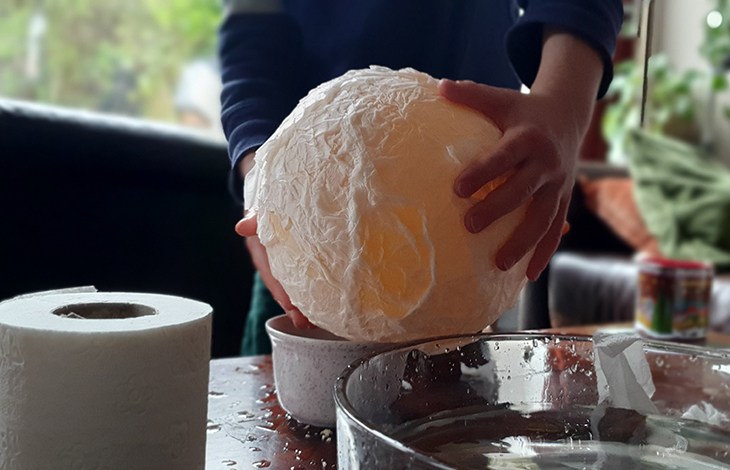 Kleine handen houden een ballon vast waar wc papier aan kleeft